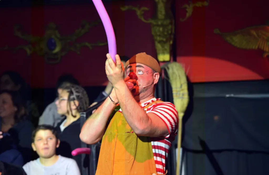 Un enfant du public participe au spectacle avec un ballon sculpté.