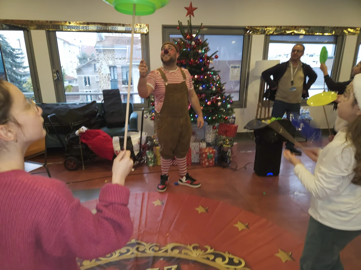 Animation de Noël dans une salle décorée, avec sapin et ballons.